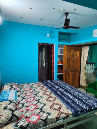 um quarto com uma cama com uma parede azul em jharana guest house em Puri