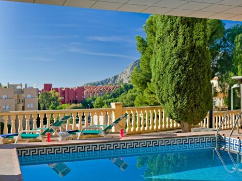 una piscina en un hotel con sillas y árboles en Apartment Raquel by Interhome, en Calpe