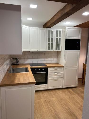 a white kitchen with white cabinets and a sink at Apartmány Horský Dvůr in Bedřichov