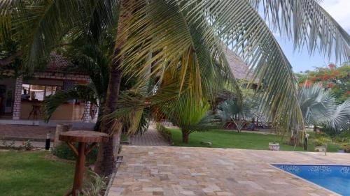 a palm tree next to a swimming pool at Kwa Mama Village Beach Resort in Dar es Salaam