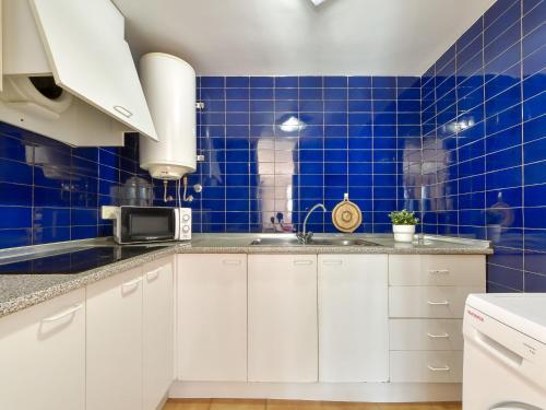 a blue tiled kitchen with white cabinets and a sink at Apartment Platja de Roses-8 by Interhome in Roses