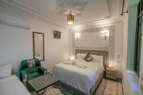 a bedroom with a white bed and a green chair at Riad dar Yamna in Fès
