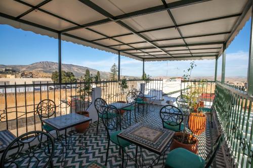 a patio with tables and chairs and a view of a field at Riad dar Yamna in Fès