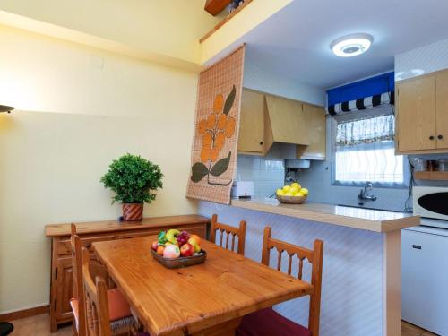 Una cocina con una mesa de madera con un bol de fruta encima. en Apartment Residencial Gran Sol by Interhome, en L'Escala