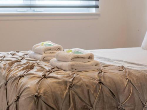 a pile of towels sitting on top of a bed at Pass the Keys Comfortable and Fabulous Family Home in Newton Mearns
