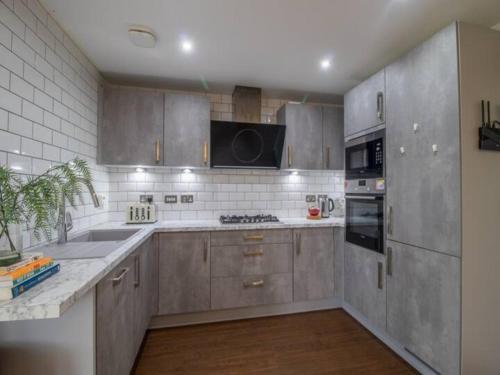 a kitchen with stainless steel appliances and wooden cabinets at Pass the Keys Comfortable and Fabulous Family Home in Newton Mearns