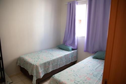 two beds in a room with purple curtains and a window at Apto otima localizacao e Wi-Fi em Serra ES in Serra
