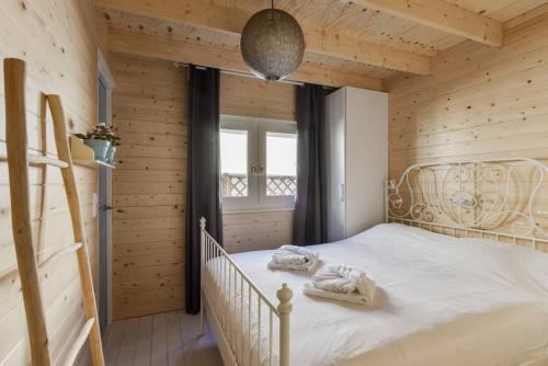 um quarto com uma cama branca num quarto de madeira em Moyo Kijani em Zandvoort