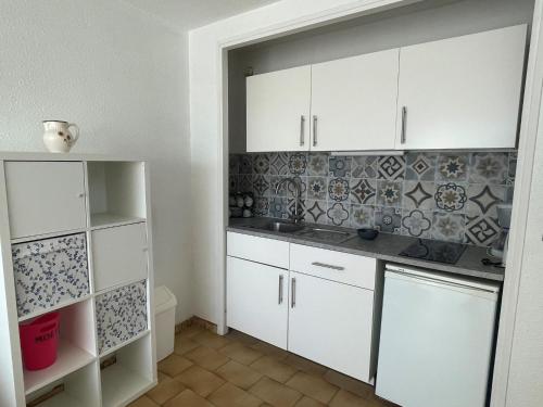 - une cuisine avec des placards blancs et un mur en carrelage dans l'établissement Apartment Arena-4 by Interhome, à La Grande Motte