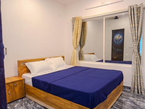 a bedroom with a bed with a blue blanket and a window at Marari Aidenz Beach Vibe Villa in Alleppey