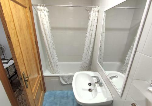 y baño blanco con lavabo y ducha. en Hostal El Molino, en Villahermosa