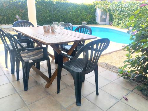 a wooden table and chairs next to a pool at Holiday Home Benicadim-1 by Interhome in Beniarbeig