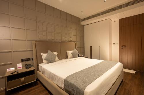 a bedroom with a large white bed and a night stand at Hotel Parsons Court in Dindigul