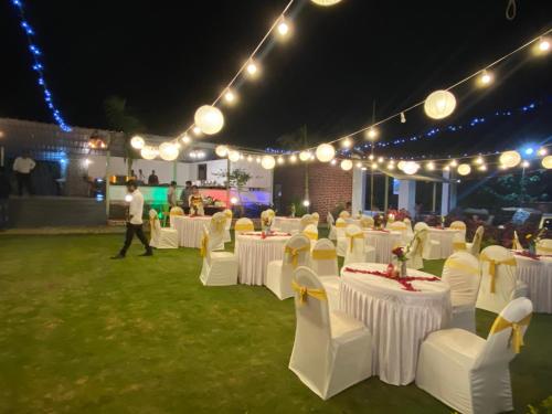 a group of tables with white chairs and lights at THE CANVAS LONAVLA in Lonavala