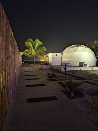 a large white building with palm trees at night at AVICENNIA BEACH DOMES in Salalah