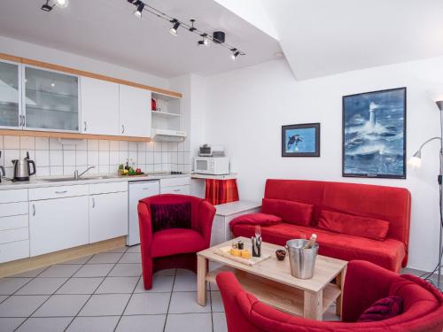 ein Wohnzimmer mit einem roten Sofa und roten Stühlen in der Unterkunft Apartment Am Deich by Interhome in Norddeich
