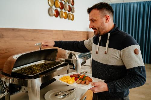 a man standing in a kitchen with a plate of food at Thermal Resort Hotel Lendava in Lendava