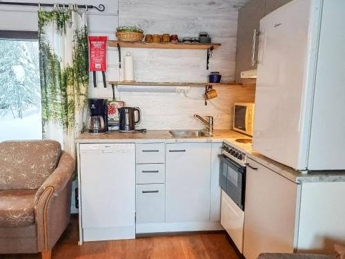 uma pequena cozinha com armários brancos e um lavatório em Holiday Home Mustalampi 4 kyyhkynen by Interhome em Ruka