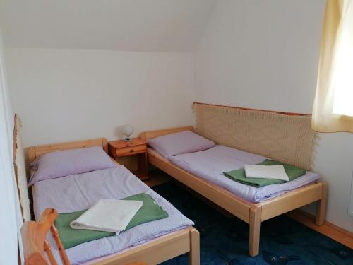 duas camas num quarto com uma mesa e uma cadeira em Gabriella Ház em Szólád