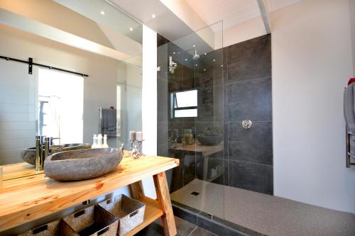 a bathroom with a stone sink and a shower at SAFFRON COTTAGE in Hermanus
