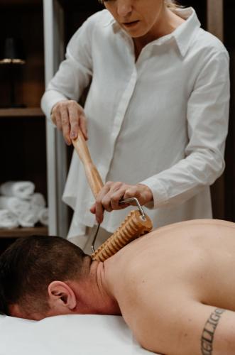 a woman cutting a mans back with a hair brush at Thermal Resort Hotel Lendava in Lendava