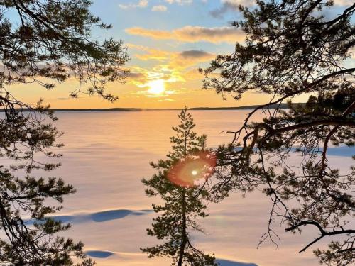 LahdenperäにあるHoliday Home Keskikallio- nuasjärvi by Interhomeの木々の水上夕日