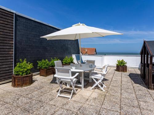 eine Terrasse mit einem Tisch und einem Sonnenschirm in der Unterkunft Apartment Cap Cabourg-22 by Interhome in Cabourg