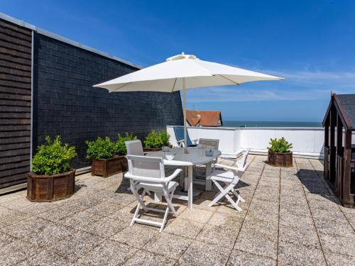 un patio avec une table et un parasol dans l'établissement Apartment Cap Cabourg-22 by Interhome, à Cabourg