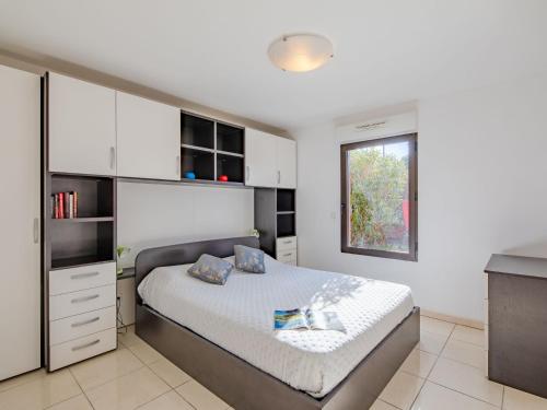 1 dormitorio con 1 cama con armarios blancos y ventana en Apartment Santa Monica-2 by Interhome, en Fréjus
