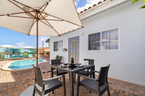 comedor con mesa, sillas y sombrilla en Little Paradise, en Noord