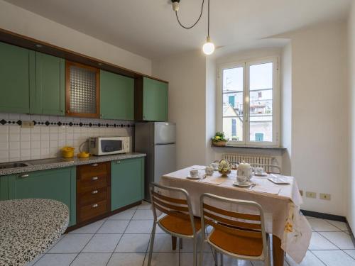 eine Küche mit grünen Schränken und einem Tisch mit Stühlen in der Unterkunft Apartment Gallesio - FLG213 by Interhome in Finale Ligure