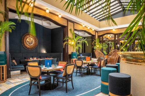 un ristorante con tavoli, sedie e piante di Hôtel l'Echiquier Opéra Paris - MGallery a Parigi