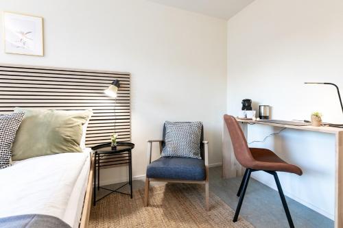 a bedroom with a bed and a chair and a desk at INN JOY Apartments - Sankt Gallen Center in St. Gallen
