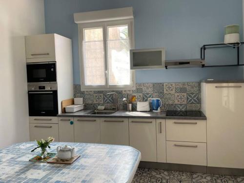 a kitchen with white cabinets and a table at Maison centre ville - 7332 in Soulac-sur-Mer
