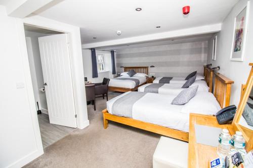 a bedroom with two beds and a desk at The Saxon Inn in Bishop Auckland