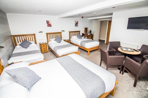 a hotel room with two beds and a desk at The Saxon Inn in Bishop Auckland