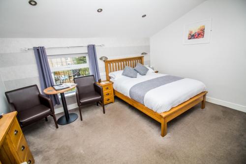 a bedroom with a bed and two chairs and a table at The Saxon Inn in Bishop Auckland