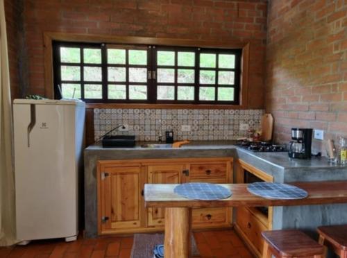 a kitchen with a sink and a refrigerator at Chalé Jequitibá- Valedaspedrasmg in Sapucaí-Mirim