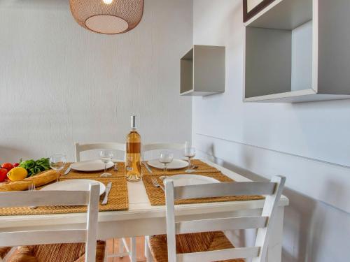 - une salle à manger avec une table, des chaises et une bouteille de vin dans l'établissement Apartment Les Rivages de Coudoulière-19 by Interhome, à Six-Fours-les-Plages