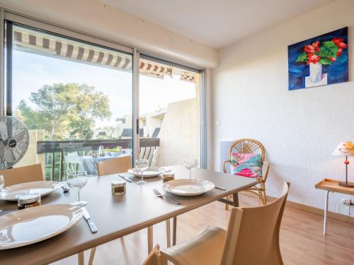 une salle à manger avec une table et des chaises et une grande fenêtre dans l'établissement Studio Les Louvans-9 by Interhome, à Saint-Aygulf