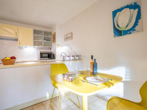 une petite cuisine avec une table jaune et des chaises jaunes dans l'établissement Studio La Galiote-2 by Interhome, à Saint-Aygulf