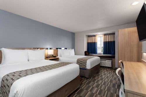 um quarto de hotel com duas camas e uma secretária em Microtel Inn and Suites - Zephyrhills em Zephyrhills