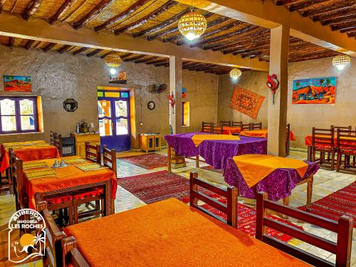 ein Restaurant mit Tischen und Stühlen mit lila Tischen in der Unterkunft Riad Les Roches Merzouga in Merzouga