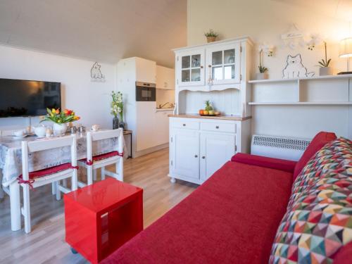 a living room with a red couch and a table at Apartment Dina with parking and shared pool by Interhome in De Haan