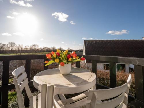 a table and chairs with a vase of flowers on a balcony at Apartment Dina with parking and shared pool by Interhome in De Haan