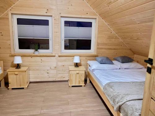 two beds in a wooden room with two windows at Domki Letniskowe Vitamin Sea in Sarbinowo