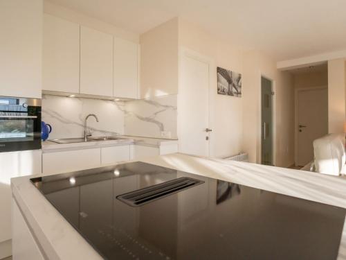 eine weiße Küche mit einer Spüle und einer Theke in der Unterkunft Apartment Blutsyde Promenade-35 by Interhome in Bredene