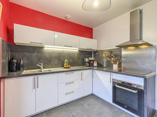 a kitchen with white cabinets and a red wall at Holiday Home Bretagne by Interhome in Carnac