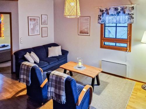 ein Wohnzimmer mit einem blauen Sofa und einem Tisch in der Unterkunft Holiday Home Alppitalo sinitähti 9 apt 3 by Interhome in Tahkovuori