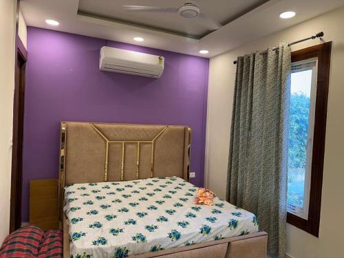 a bedroom with purple walls and a bed and a window at Serene, charming and party friendly Farmhouse sec 150 Noida in Greater Noida